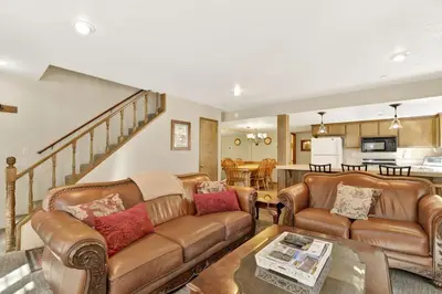 a living room with leather furniture and a kitchen at Slope Side Getaway at Big Bear - Central Duplex Retreat Chalet in Big Bear Lake