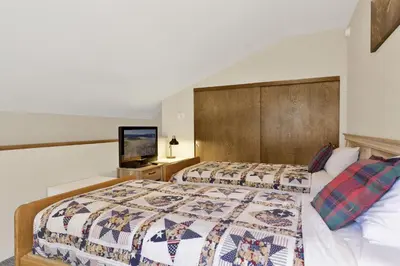 a bedroom with two beds and a flat screen tv at Slope Side Getaway at Big Bear - Central Duplex Retreat Chalet in Big Bear Lake