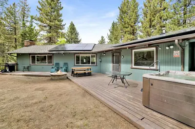 a green house with a deck with a picnic table at Arlberg Village Haus Game Room Walk to the Slopes in Big Bear Lake