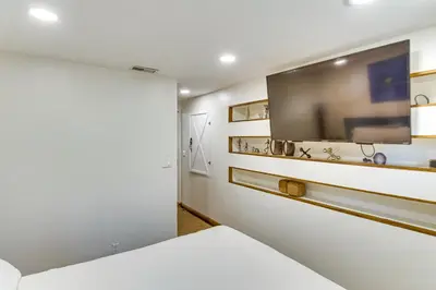a white bedroom with a flat screen tv on the wall at Golf and Swim! Pine Mtn Club Retreat with Game Area in Pine Mountain Club