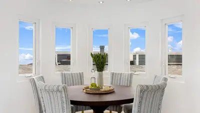 a dining room with a table and chairs and windows at Walk to Manhattan Beach Pier Ocean Views Balcony Peloton Casa Del Mar by AvantStay in Manhattan Beach