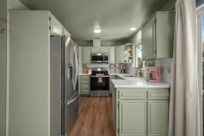 a kitchen with green cabinets and a refrigerator at The Quirky Bloom-Whimsical Guest house in Upland