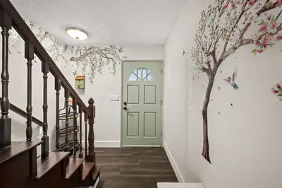 a hallway with a door with a tree mural on the wall at The Quirky Bloom-Whimsical Guest house in Upland