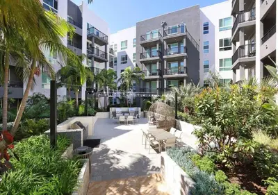 a courtyard in a building with chairs and palm trees at Bright & Cozy Getaway with Pool Free Parking 10 mins Disneyland in Santa Ana