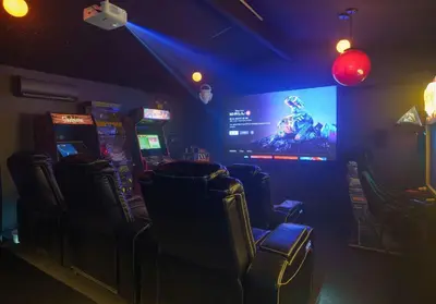 a video game room with chairs and a large screen at Imagination Kingdom by OC Adventure Homes in Garden Grove