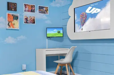 a room with a tv and a table and a chair at Imagination Kingdom by OC Adventure Homes in Garden Grove