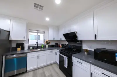 a kitchen with white cabinets and black appliances at Modern Private Room in Shared Home -Walk to USC in Los Angeles