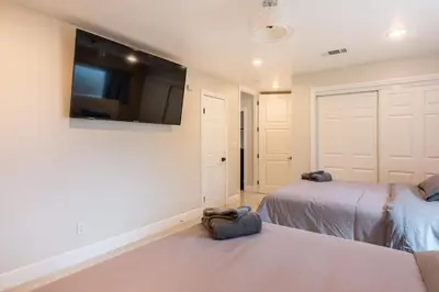 a bedroom with two beds and a flat screen tv at Spacious 5 BR Brand New House LAX in Inglewood