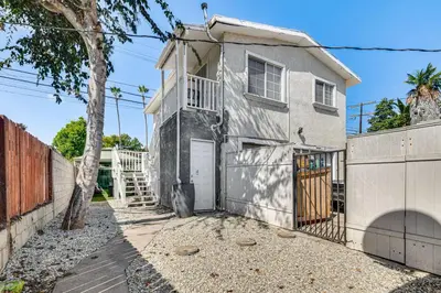 a white house with a gate and a fence at Near Hospitals and Metrolink Access LA Getaway in Los Angeles
