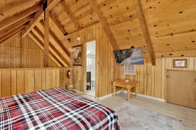 a bedroom with a bed in a room with wooden walls at Lakeview Pines Log Cabin - Custom Built Village Log Cabin Retreat w/ Hot Tub, Pool Table in Big Bear Lake