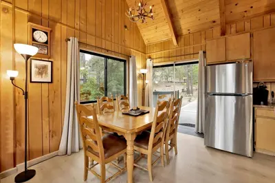 a dining room with a table and a refrigerator at Lakeview Pines Log Cabin - Custom Built Village Log Cabin Retreat w/ Hot Tub, Pool Table in Big Bear Lake
