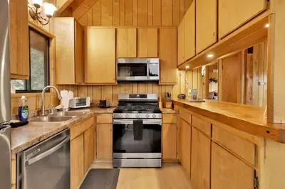 a kitchen with a stove and a microwave at Lakeview Pines Log Cabin - Custom Built Village Log Cabin Retreat w/ Hot Tub, Pool Table in Big Bear Lake
