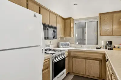 a kitchen with wooden cabinets and a white refrigerator at Summit Ski Resort Mountain View Condo - Walk to Snow Summit in Big Bear Lake