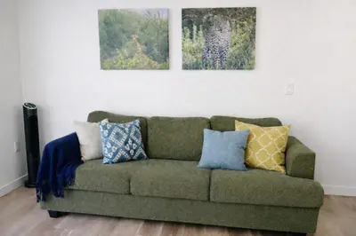 a living room with a green couch with pillows at Heart of Hollywood Walk of Fame - Free Parking, Pool, Gym, Rooftop Views, centrally located, WIFI in Los Angeles
