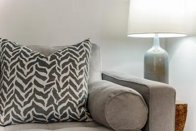 a couch with a pillow sitting next to a lamp at Quiet 1- bedroom condo near LAX, SoFi, and the Beach in Los Angeles