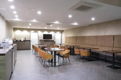 a restaurant with tables and chairs and a television at Hotel Xilo Glendale in Glendale