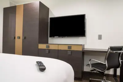 a room with a tv and a chair with a remote control at Hotel Xilo Glendale in Glendale