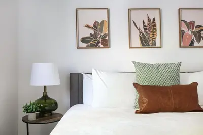 a bedroom with a white bed with four pictures on the wall at Luxury 2BR Apartment Great Area with Parking in Glendale