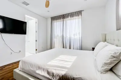 a white bedroom with a bed and a television at Modern 4BR Villa Spacious Stylish In Prime Location in Los Angeles