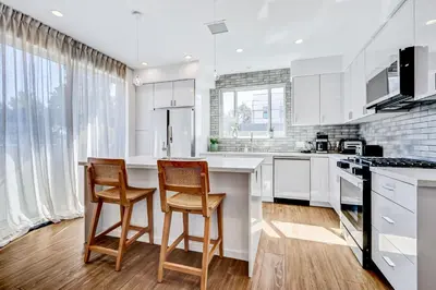 a kitchen with white cabinets and a table and chairs at Modern 4BR Villa Spacious Stylish In Prime Location in Los Angeles