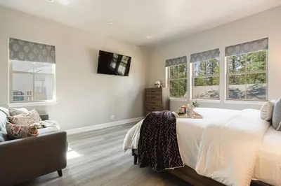 a bedroom with a bed and a couch and windows at The Reel Deal, Luxury Family Cabin by Alpine Slide in Big Bear Lake