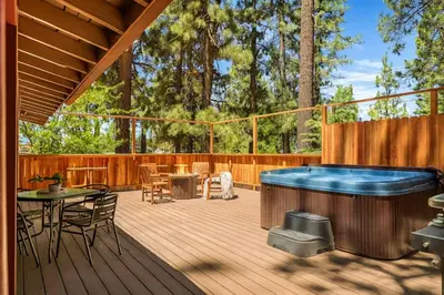 a deck with a hot tub and a table and chairs at Lawliss Hideout in Big Bear Lake in Big Bear Lake