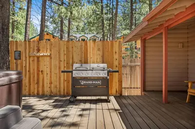 a grill sitting on a wooden deck next to a fence at Lawliss Hideout in Big Bear Lake in Big Bear Lake