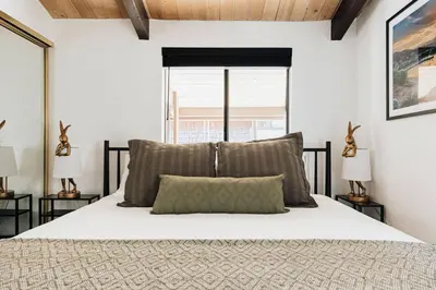 a bedroom with a bed and two lamps and a window at Solace Cabin in Big Bear Lake