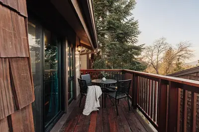 a wooden balcony with a table and chairs on a porch at Solace Cabin in Big Bear Lake