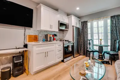 a kitchen with white cabinets and a glass table at Walk to Hollywood Blvd Chic LA Studio with Patio! in Los Angeles