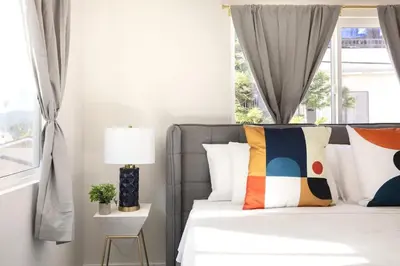 a bedroom with a bed with colorful pillows and a window at Relax in Spacious 3BR Apt Sleeps 8 and Parking in Glendale