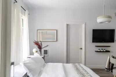 a white bedroom with a bed with pillows and a tv at Cozy Studio in Hollywood in Los Angeles