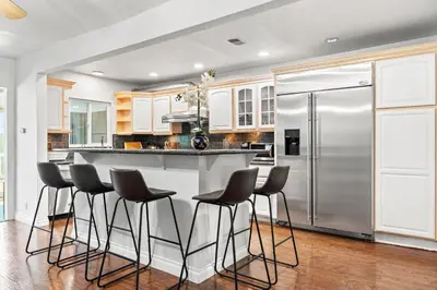 a kitchen with a bar with stools and a refrigerator at Spacious Family Retreat in San Dimas Great Location in Covina
