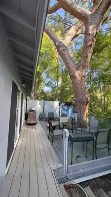 a deck with tables and chairs and a tree at Joyful Place in Sherman Oaks
