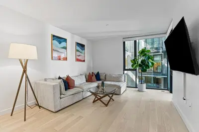 a living room with a couch and a flat screen tv at Pearl Coast - Modern 2BR with Rooftop Pool & Views in Los Angeles