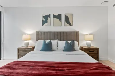 a bedroom with a large bed with blue pillows at Pearl Coast - Modern 2BR with Rooftop Pool & Views in Los Angeles