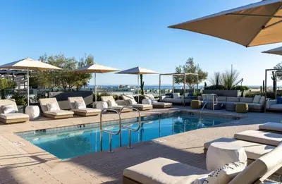 a swimming pool with lounge chairs and umbrellas at Pearl Coast - Modern 2BR with Rooftop Pool & Views in Los Angeles