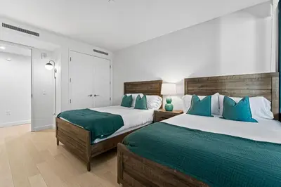 a bedroom with two beds with blue pillows at Pearl Coast - Modern 2BR with Rooftop Pool & Views in Los Angeles