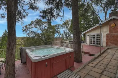 a hot tub on a patio with trees at Emerald Arrowhead Haus - For 6 in Lake Arrowhead