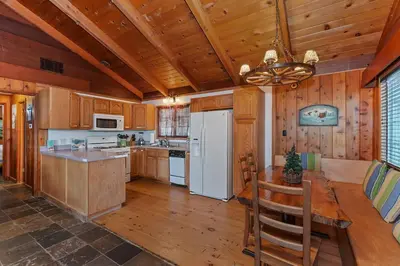 a kitchen with a table and a white refrigerator at Emerald Arrowhead Haus - For 6 in Lake Arrowhead