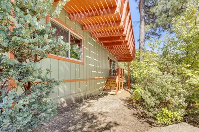 a house with an orange pergola on the side of it at Deck and Views Modern Cabin Near Lake Arrowhead! in Lake Arrowhead