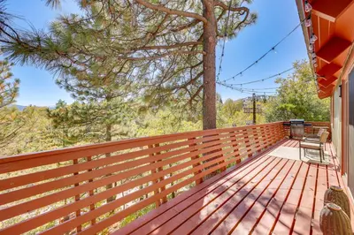 a wooden deck with two chairs on a house at Deck and Views Modern Cabin Near Lake Arrowhead! in Lake Arrowhead