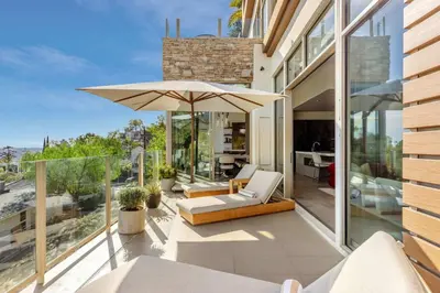 a patio with an umbrella and chairs on a house at Chateau Lumier by Stay Awhile in Los Angeles