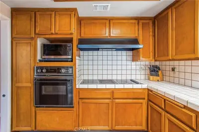 a kitchen with wooden cabinets and a stove top oven at Spacious Fully Furnished 3BR Fully Fenced Home in Riverside