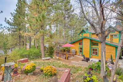 a yellow house with a deck in the woods at 3 Mi to Snow Summit Charming Home with Fenced Yard in Big Bear Lake