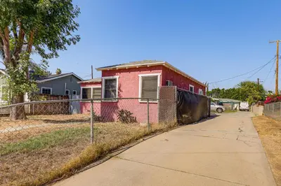 a red house with a fence next to a sidewalk at High Walkability! Extended Stay in Riverside in Riverside