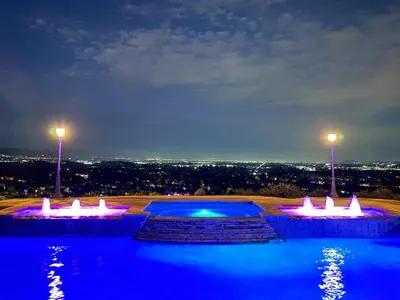 a swimming pool with lights and a city at night at Modern Hilltop Retreat in Lakeside Park