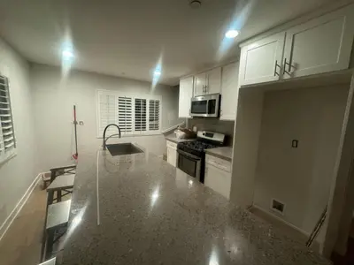 a kitchen with white cabinets and a granite counter top at Soulistic Vibes Normandie in Los Angeles
