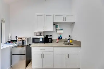 a white kitchen with white cabinets and appliances at Walk to Main St! Pet-Friendly Alhambra Studio in Alhambra