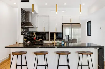 a kitchen with white cabinets and bar stools at Platinum Suite LA in Los Angeles
